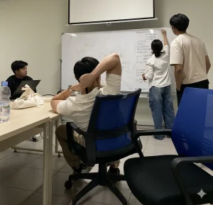 Hình ảnh thực tế nhóm nhân viên đang thảo luận ý tưởng trên bảng trắng Ấn Độ cao cấp Bavico tại văn phòng quận 1. Bảng có bề mặt trắng sáng, chống lóa tốt dưới ánh đèn điện, giúp nội dung hiển thị rõ nét từ mọi góc nhìn.